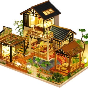 May include: A wooden dollhouse kit with a Japanese-style design. The dollhouse features a two-story structure with a balcony, a pergola, and a small pond. The dollhouse is made of wood and has a light brown finish. The dollhouse is lit up with small LED lights.