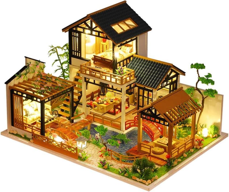 May include: A wooden dollhouse kit with a Japanese-style design. The dollhouse features a two-story structure with a balcony, a pergola, and a small pond. The dollhouse is made of wood and has a light brown finish. The dollhouse is lit up with small LED lights.