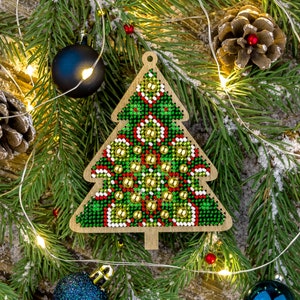 May include: A green, red, and gold Christmas tree ornament with a beaded design. The ornament is made of wood and has a string for hanging.