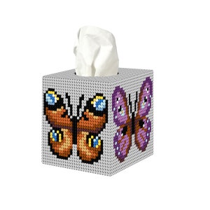 May include: A white tissue box cover with a brown and yellow butterfly on one side and a purple butterfly on the other side.