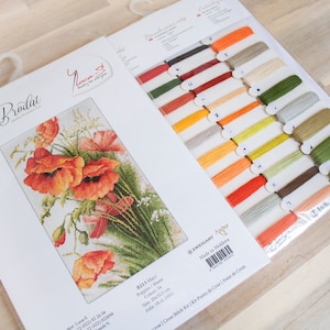 May include: A cross-stitch kit featuring a floral design of orange and red poppies. The kit includes a printed pattern, embroidery floss in various colors, and a needle. The kit is labeled "Set de Broderie" and "Luca-S".