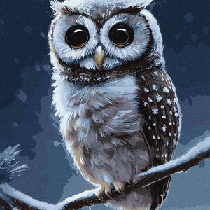 Puede incluir: Un b&uacute;ho blanco con grandes ojos oscuros se posa en una rama sobre un fondo azul. El b&uacute;ho tiene marcas marrones y negras en sus plumas.