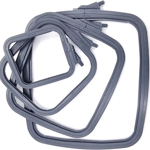 May include: A collection of gray, square embroidery hoops in various sizes, stacked and overlapping. Each hoop has a locking mechanism and is labeled with its size in millimeters. The largest hoop is labeled "No. 4 - 280 mm".