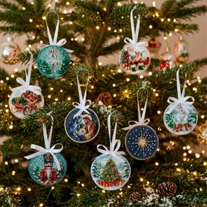 May include: A collection of round Christmas ornaments with various designs, including a ballerina, Santa Claus, a nativity scene, a nutcracker, a Christmas tree, and a snowflake. Each ornament is adorned with a white ribbon for hanging.