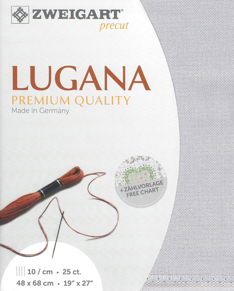 Peut inclure: Un tissu Aida blanc avec du fil &agrave; broder marron et une aiguille. Le tissu est &eacute;tiquet&eacute; "Lugana Premium Quality Made in Germany" et a les dimensions 19" x 27" (48 x 68 cm). Un cercle avec le texte "+ Z&Auml;HLVORLAGE FREE CHART" se trouve dans le coin sup&eacute;rieur droit.