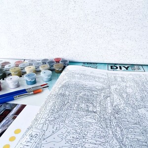 Puede incluir: Un kit de pintura por n&uacute;meros con un dise&ntilde;o de paisaje urbano. El kit incluye un lienzo, pinceles y peque&ntilde;os frascos de pintura acr&iacute;lica. El lienzo est&aacute; parcialmente rellenado con n&uacute;meros, que indican d&oacute;nde aplicar cada color de pintura. El kit tambi&eacute;n incluye el texto "DIY & EASY NO. 20" y "DO IT YOURSELF".