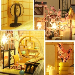 May include: A miniature dollhouse with a wooden frame and a white lace curtain. The dollhouse features a small, wooden table with a lamp and a shelf with a variety of miniature items. The dollhouse is decorated with pink flowers and a small, wooden tree.
