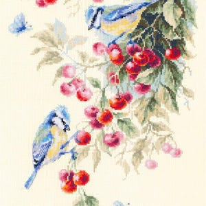May include: Cross-stitch design featuring two blue and yellow birds perched on a cherry tree branch. The tree is laden with red cherries and green leaves, with two blue butterflies fluttering nearby. The background is a light cream color.