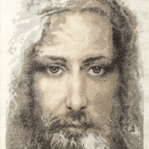 May include: A black and white cross-stitch image of a man's face. The man has a beard and long hair. The image is on a white background.