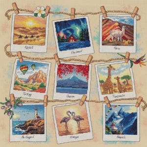 May include: A cross-stitch embroidery featuring nine square polaroid-style photos hanging on a rope with wooden clothespins. The images depict scenes from Egypt, Finland, Peru, Turkey, Japan, Tanzania, Portugal, Kenya, and Nepal, each labeled with its country name in cursive script.