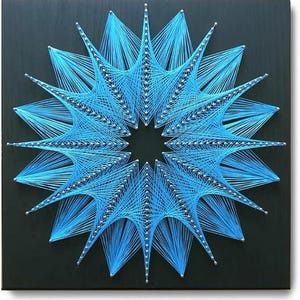 May include: A square black wooden board featuring a geometric string art design. Bright blue thread is wrapped around silver nails to create a complex, star-shaped pattern with multiple radiating points and a hollow centre, forming a symmetrical star.
