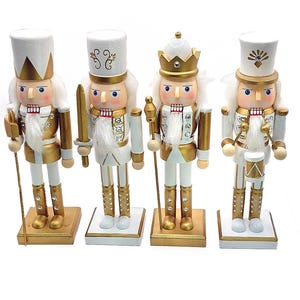 May include: Four decorative nutcrackers in a row, each with a unique design. They are dressed in white and gold uniforms with white wigs and hats. Each nutcracker stands on a gold and white base, with various accessories like swords and drums.