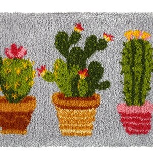 May include: A gray rug with three potted cactus plants. The cactus plants are green with yellow and red flowers. The pots are brown, orange, and pink.