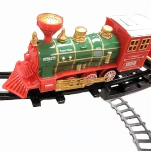 May include: A red and green toy train with a black track. The train has a red engine with a gold bell and a green caboose. The engine has the words "Power Train" and "Power & Speed" printed on it. The caboose has the number "1059" printed on it.