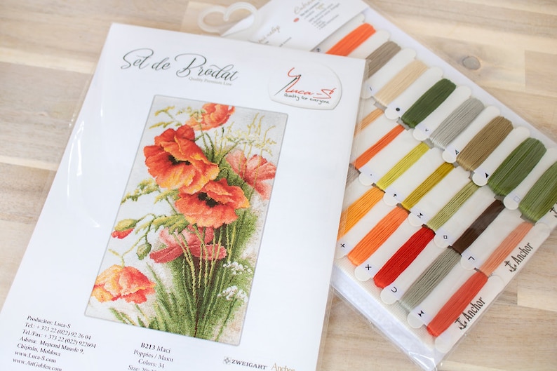May include: A cross-stitch kit featuring a vibrant floral design of orange poppies and green foliage. The kit includes a printed pattern, embroidery floss in various colors, and the text "Set de Brodat".