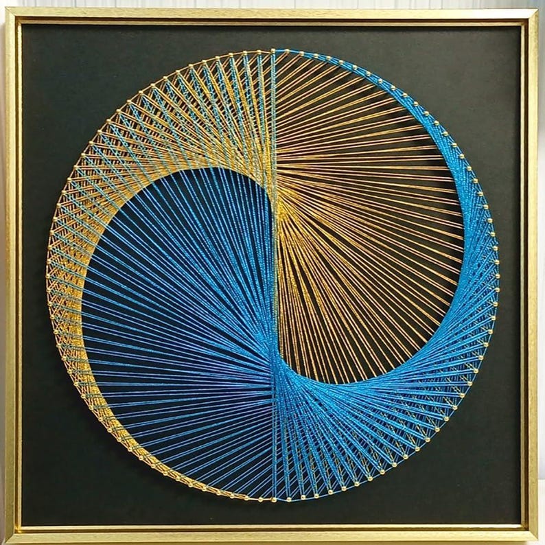 May include: A square wall art piece featuring a circular string art design on a black background. The design uses metallic gold and bright blue threads wrapped around small pins to create a swirling, geometric pattern inside a gold frame.