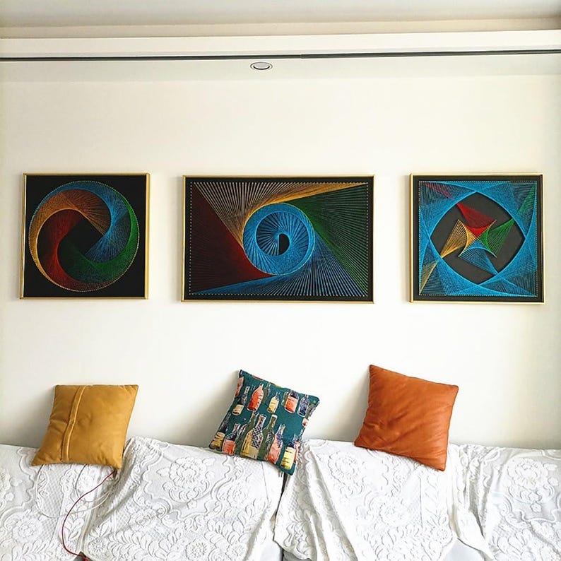 May include: Three framed string art pieces featuring geometric patterns in vibrant colours on black backgrounds. The left piece is circular, the centre is rectangular with a spiral, and the right is square with a multi-pointed star design.