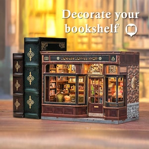 May include: A miniature wooden Corner Coffee Shop model with detailed interior and exterior features, including a brick facade and a sign. The model is displayed next to three decorative books. The text "Decorate your bookshelf" is visible.