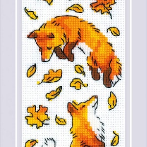 May include: Cross-stitch artwork featuring three orange foxes in various poses, surrounded by yellow autumn leaves. The foxes are depicted in a detailed, textured style, with a white background and a white border.