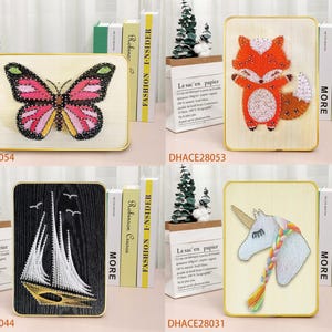 May include: Four wooden frames with string art designs. The designs are a butterfly, a fox, a sailboat, and a unicorn. The frames are all the same size and have a gold trim.