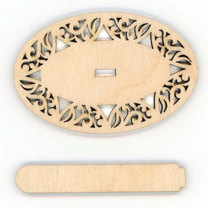 May include: A wooden oval-shaped frame with a decorative cutout design. The frame has a slot in the center and is accompanied by a separate wooden piece.
