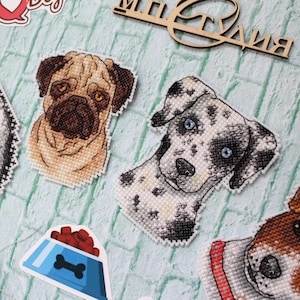 May include: Four cross-stitch dog portraits of a husky, pug, dalmatian, and jack russell terrier. The portraits are surrounded by dog-themed stickers, including a dog house, a bone, a collar, and a bowl of dog food.