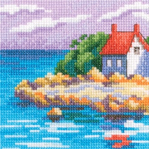 May include: A cross-stitch pattern of a blue house with a red roof on a rocky island. The house has a white trim and two windows. The island is surrounded by blue water with white waves. The sky is purple with white clouds.