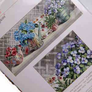 Pu&ograve; includere: Schemi a punto croce con disegni di nature morte floreali. I modelli raffigurano vasi e piatti pieni di fiori colorati, tra cui ortensie blu e fiori rossi, su uno sfondo grigio. I disegni sono dettagliati e intricati, mostrando una variet&agrave; di colori.