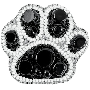 May include: Black and white beaded paw print with a raised design. The paw print is made of small, round beads.