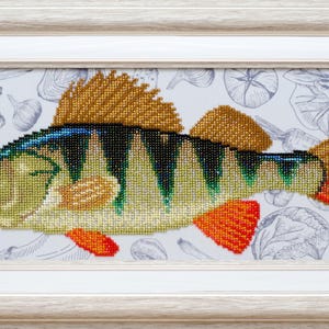 May include: A framed diamond painting of a perch fish featuring green, yellow, and orange scales with a spiky dorsal fin. The fish is set against a light background with faint, gray line-art illustrations of various vegetables.