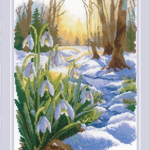 May include: Cross-stitch of a winter forest scene with snow-covered ground and bare trees. The foreground features a cluster of snowdrop flowers with white petals and green leaves. The background shows a path leading into the sunlit distance.