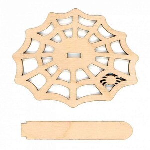 May include: A wooden cutout of a spider web with a small spider in the center. The web is attached to a wooden stand.