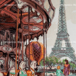 May include: A cross-stitch design featuring a carousel with two white horses and a hot air balloon, set against the backdrop of the Eiffel Tower in Paris. The text "Momentos Magicos" appears multiple times in the design.