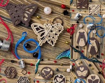 May include: A collection of wooden laser cut ornaments featuring various designs, including butterflies, birds, bears, and geometric patterns. The ornaments are arranged on a wooden surface with colourful beads and thread.