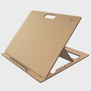 May include: A light brown, angled drafting board with a handle cut-out at the top. The board is supported by a folding stand. The word "Rasa" is printed on the top right corner.