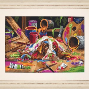 May include: A brown and white dog covered in colourful paint lies on a wooden floor surrounded by paint cans, brushes, and a paint palette.