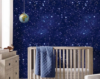 May include: A white cot with a blue quilted blanket and a white armchair with a grey plush toy in a nursery with a blue and white starry wall mural.