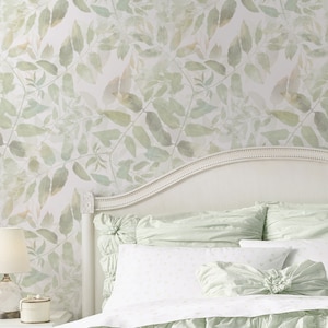 Puede incluir: Una cama blanca con un edredón y almohadas de color verde claro. El edredón tiene un diseño con volantes y las almohadas también son con volantes. La cabecera es blanca y tiene una parte superior curva. La pared detrás de la cama está cubierta con un papel tapiz verde claro con un patrón de hojas.