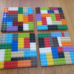 May include: Four square coasters made of colorful Lego bricks. Each coaster is a different pattern of red, blue, green, yellow, orange, white, black, brown, and gray Lego bricks.