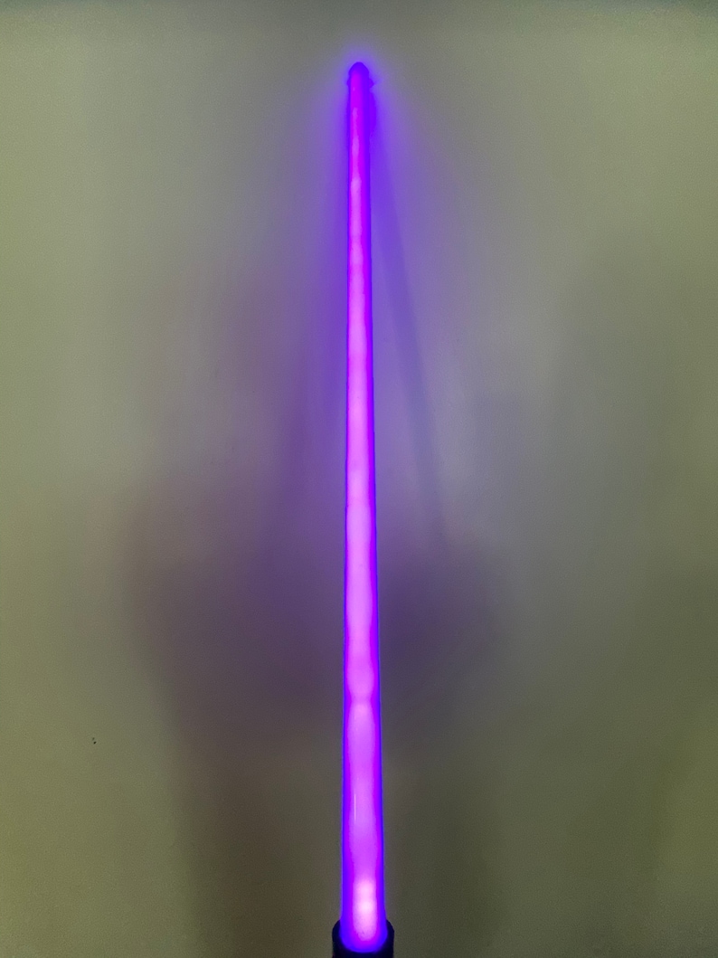 以下が含まれることがあります： 光る刃を持つ紫色のライトセーバーのおもちゃ
