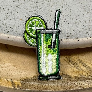 Peut inclure: Patch brodé vert d'une margarita à la lime avec une paille. La margarita est dans un grand verre avec une garniture de quartiers de lime.
