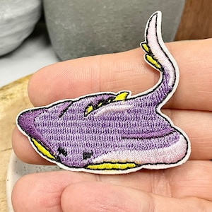 May include: Purple and yellow embroidered iron-on patch of a stingray.