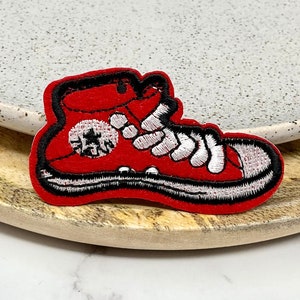 May include: Red embroidered iron-on patch of a high-top sneaker with white laces and a white star logo.