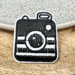 Peut inclure: Patch brodé noir et blanc représentant un appareil photo vintage à repasser.
