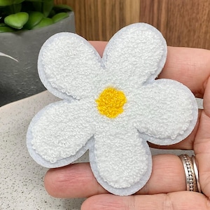Peut inclure: Patch de fleur en feutre blanc avec un centre jaune. La fleur a cinq pétales et mesure environ 7,5 cm de diamètre.