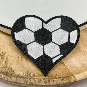 May include: Black and white heart-shaped patch with an embroidered soccer ball design.