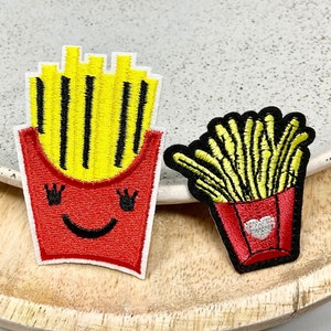 May include: Two embroidered iron-on patches featuring a cartoon depiction of chips in a red box. One patch has a smiling face and the other has a white heart.