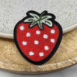 Peut inclure: Patch brodé de fraise rouge avec des pois blancs et des feuilles vertes.