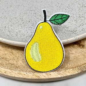 May include: A yellow pear with a green leaf embroidered patch. The pear is outlined in black and has a textured appearance.
