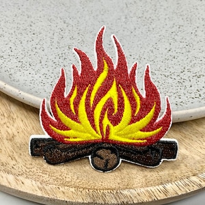 Può includere: Toppa ricamata termoadesiva con un falò con fiamme rosse e gialle e tronchi marroni.